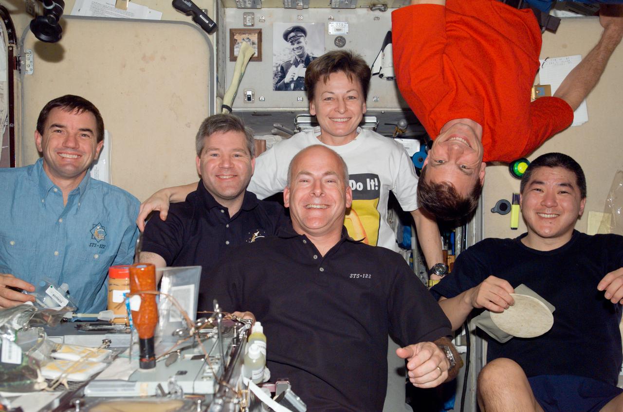 S122-E-009723 (17 Feb. 2008) --- STS-122 and Expedition 16 crewmembers share a meal at the galley in the Zvezda Service Module of the International Space Station. Pictured from the left are NASA astronauts Rex Walheim, STS-122 mission specialist; Steve Frick, STS-122 commander; Peggy Whitson, Expedition 16 commander; Alan Poindexter, STS-122 pilot; Stanley Love and Daniel Tani, both STS-122 mission specialists.