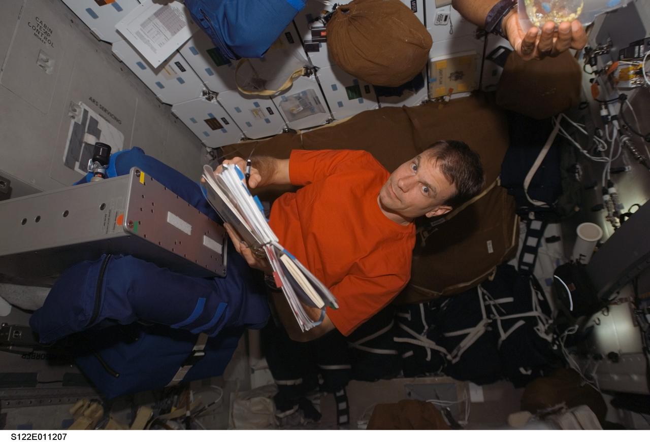 S122-E-011207 (18 Feb. 2008) --- Astronaut Stanley Love, STS-122 mission specialist, looks over procedures checklists while occupying the bicycle ergometer on the middeck of the Space Shuttle Atlantis.