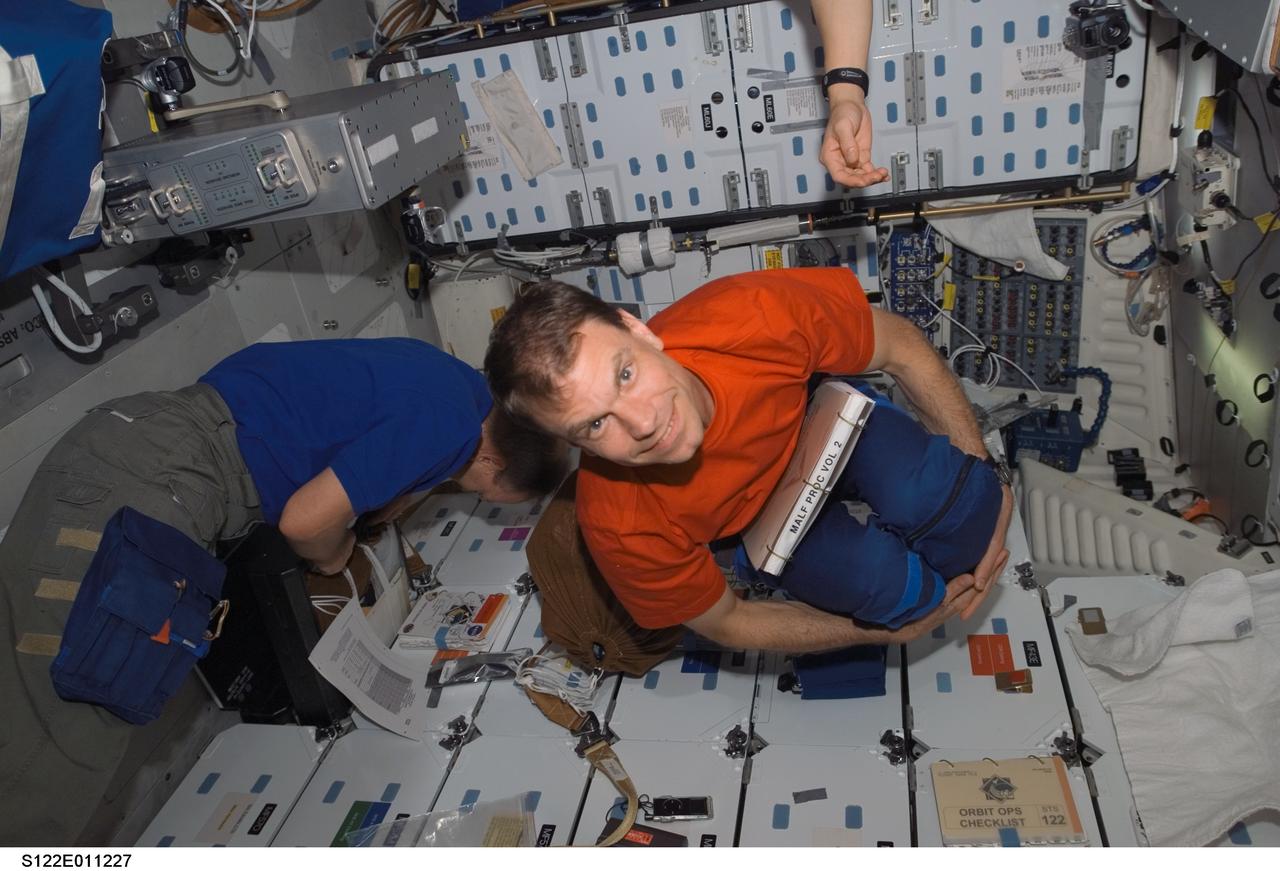 S122-E-011227 (18 Feb. 2008) --- NASA astronaut Stanley Love, STS-122 mission specialist, poses for a photo as he floats on the middeck of Space Shuttle Atlantis. European Space Agency (ESA) astronaut Hans Schlegel, mission specialist, is visible at left.