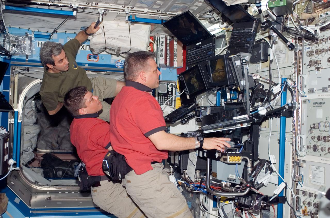 S123-E-005937 (13 March 2008) --- NASA astronauts Gregory H. Johnson (foreground), STS-123 pilot; and Robert L. Behnken, mission specialist, work the controls of the station's robotic Canadarm2 in the Destiny laboratory of the International Space Station while Space Shuttle Endeavour is docked with the station. European Space Agency (ESA) astronaut Leopold Eyharts, mission specialist, looks on.