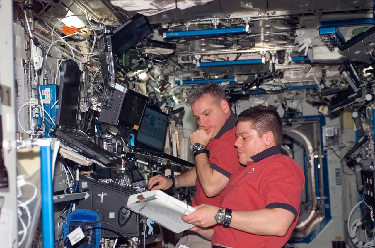 S123-E-005942 (13 March 2008) --- NASA astronauts Gregory H. Johnson, STS-123 pilot; and Robert L. Behnken (foreground), mission specialist, work the controls of the station's robotic Canadarm2 in the Destiny laboratory of the International Space Station while Space Shuttle Endeavour is docked with the station.