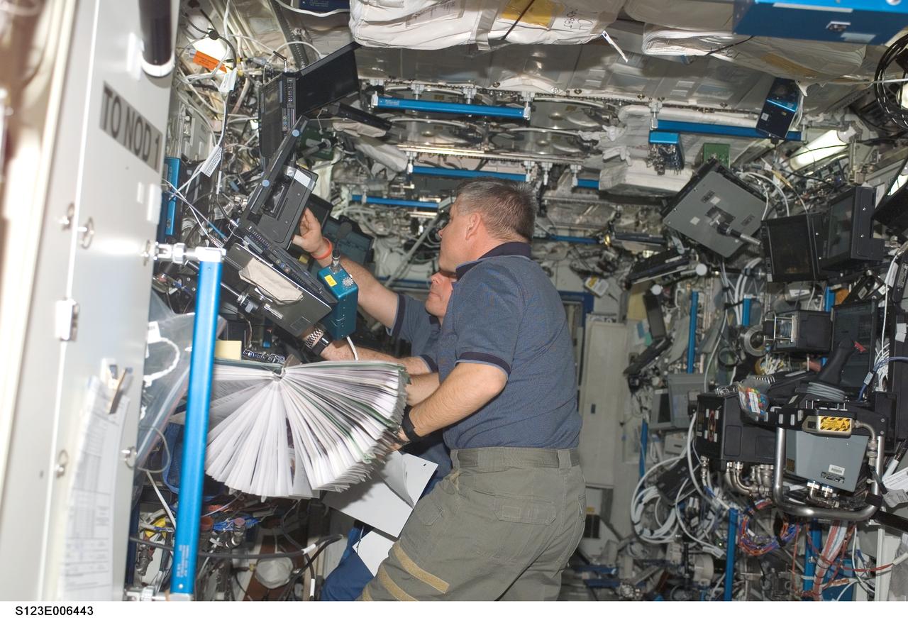 S123-E-006443 (16 March 2008) --- Astronauts Gregory H. Johnson, STS-123 pilot; and Garrett Reisman (partially obscured), Expedition 16 flight engineer, work the controls of the space station's robotic Canadarm2 in the Destiny laboratory of the International Space Station while Space Shuttle Endeavour is docked with the station.