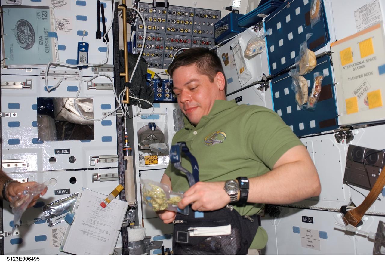 S123-E-006495 (12 March 2008) --- Astronaut Robert L. Behnken, STS-123 mission specialist, opens a food package near the galley on the middeck of Space Shuttle Endeavour while docked with the International Space Station.