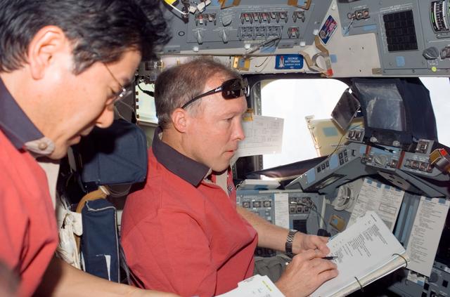 NASA image: Gorie and Doi look over crew procedures on aft FD of Space Shuttle Endeavour