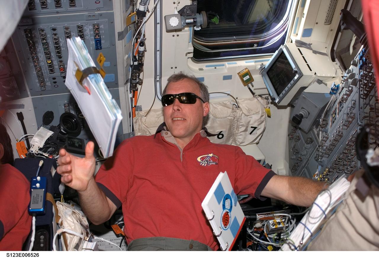 S123-E-006526 (13 March 2008) --- Astronaut Dominic Gorie, STS-123 commander, reaches for a procedures checklist floating freely on the aft flight deck of Space Shuttle Endeavour while docked with the International Space Station.