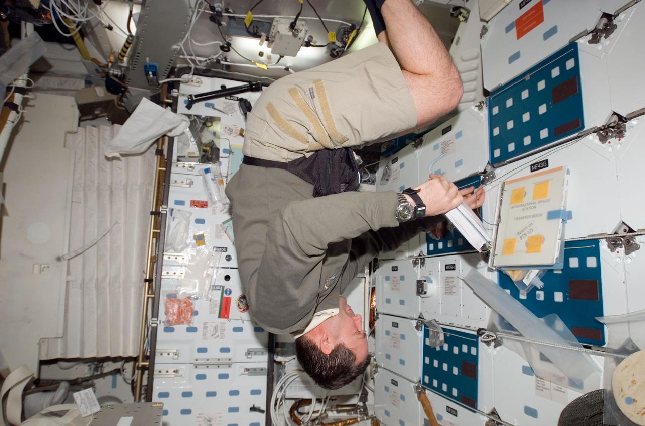 S123-E-006666 (17 March 2008) --- Astronaut Mike Foreman, STS-123 mission specialist, floating upside-down, looks over a checklist on the middeck of Space Shuttle Endeavour while docked with the International Space Station.