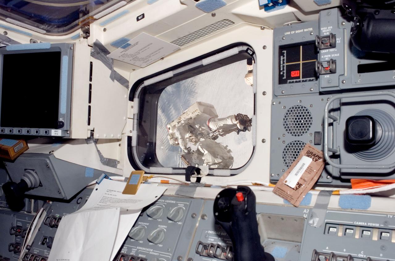 S123-E-006749 (17/18 March 2008) --- Visible through a window on Endeavour's aft flight deck, astronaut Rick Linnehan, STS-123 mission specialist, participates in the mission's third scheduled session of extravehicular activity (EVA) as construction and maintenance continue on the International Space Station. During the 6-hour, 53-minute spacewalk, Linnehan and astronaut Robert L. Behnken (out of frame), mission specialist, installed a spare-parts platform and tool-handling assembly for Dextre, also known as the Special Purpose Dextrous Manipulator (SPDM). Among other tasks, they also checked out and calibrated Dextre's end effector and attached critical spare parts to an external stowage platform. The new robotic system is scheduled to be activated on a power and data grapple fixture located on the Destiny laboratory on flight day nine.
