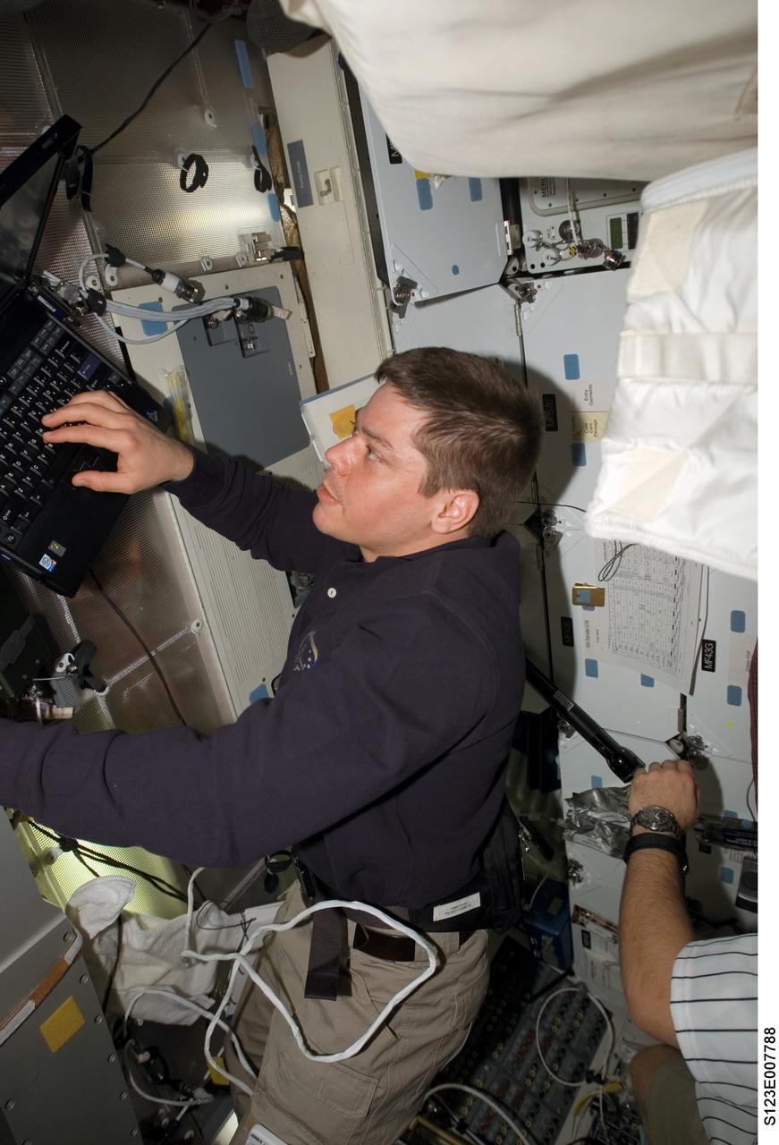 S123-E-007788 (19 March 2008) --- Astronaut Robert L. Behnken, STS-123 mission specialist, uses a computer on the middeck of Space Shuttle Endeavour while docked with the International Space Station.