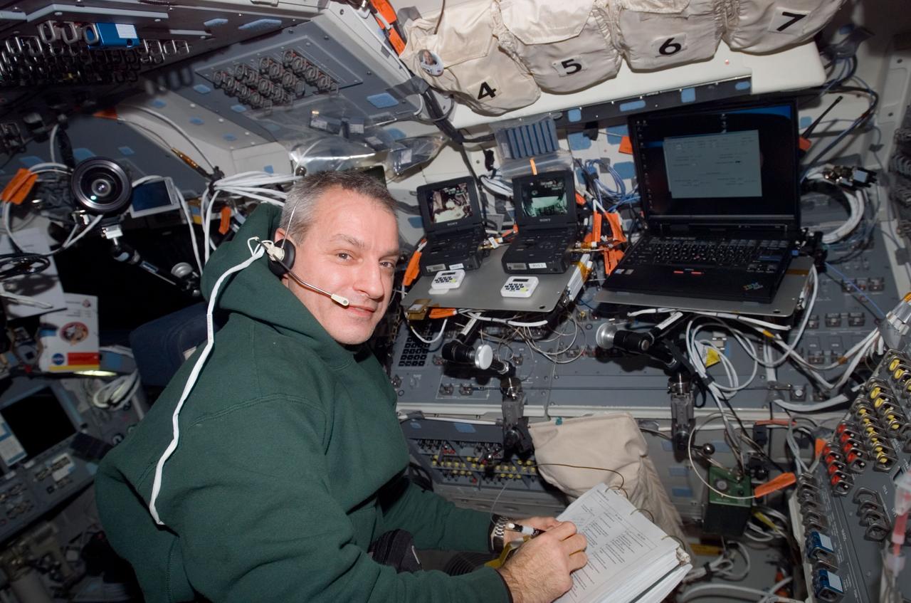 S123-E-007813 (20 March 2008) --- Astronaut Rick Linnehan, STS-123 mission specialist, uses a communication system while looking over a checklist on the flight deck of Space Shuttle Endeavour while docked with the International Space Station.
