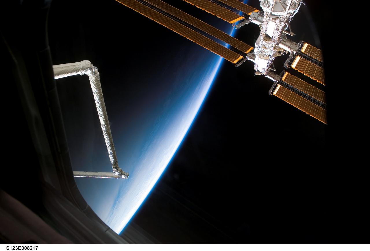 S123-E-008217 (21 March 2008) --- Space Shuttle Endeavour's Remote Manipulator System/Orbiter Boom Sensor System (RMS/OBSS) and a portion of the International Space Station's (ISS) solar array panels are photographed by a STS-123 crewmember through a window on Endeavour while docked with the station. The blackness of space and Earth's horizon provide the backdrop for the scene.