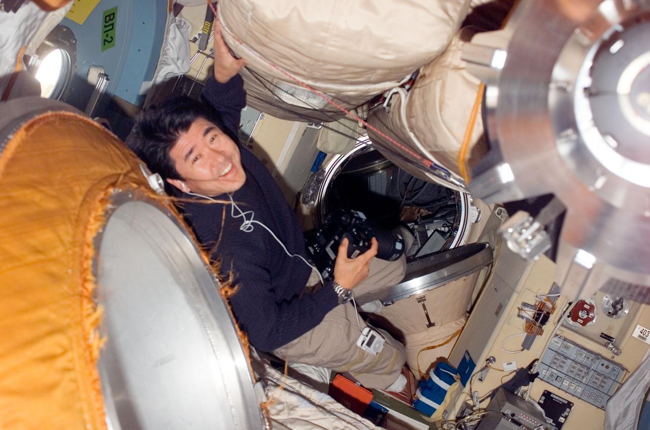 S123-E-008339 (21 March 2008) --- Japan Aerospace Exploration Agency (JAXA) astronaut Takao Doi, STS-123 mission specialist, holds a still camera in the Pirs Docking Compartment of the International Space Station while Space Shuttle Endeavour is docked with the station.