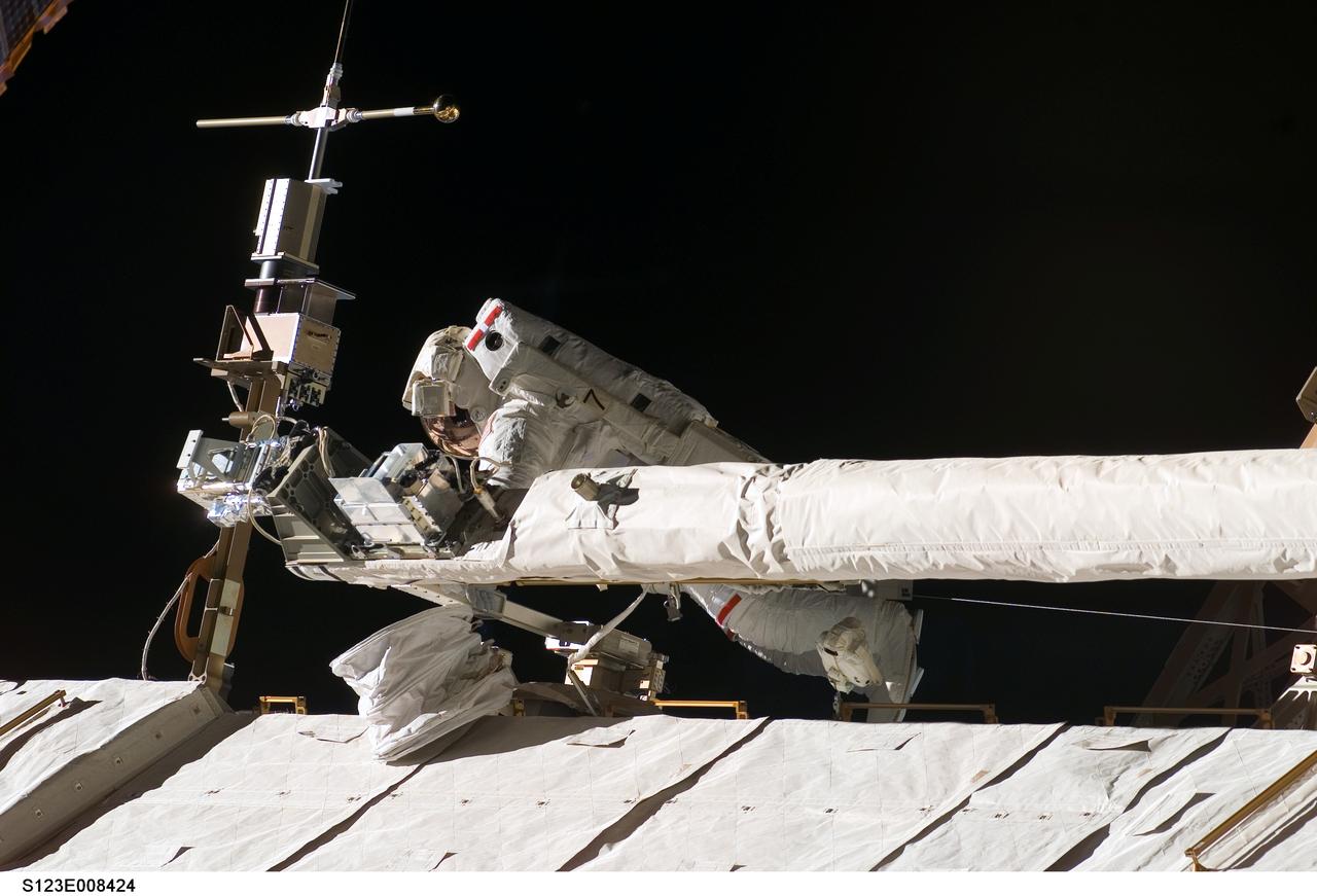 S123-E-008424  (23 March 2008) --- Astronaut Mike Foreman, STS-123 mission specialist, helps to tie down the Orbiter Boom  Sensor System  on the International Space Station's S1 truss during EVA 5 on March 22. The structure at the end of the boom is a transmission device for laser imagery from the laser devices used for scanning the thermal protection system.