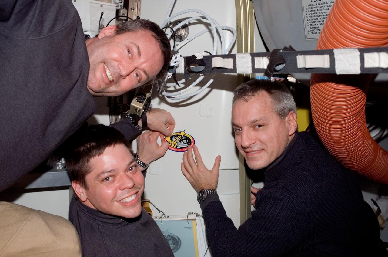 S123-E-008756 (23 March 2008) --- Astronauts Mike Foreman (left), Robert L. Behnken and Rick Linnehan, all STS-123 mission specialists, add the STS-123 patch to the growing collection of insignias representing crews who have performed spacewalks from the Quest Airlock of the International Space Station.