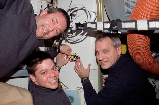 NASA image: Foreman,Behnken,and Linnehan place STS-123 patch on wall in the A/L during Joint Operations