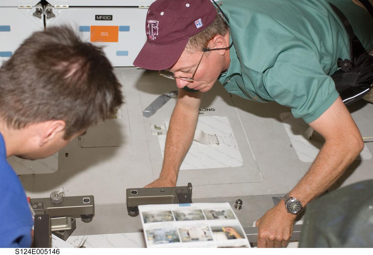 S124-E-005146 (1 June 2008) --- NASA astronaut Mike Fossum (right) and Japan Aerospace Exploration Agency (JAXA) astronaut Akihiko Hoshide, both STS-124 mission specialists, work on the middeck of Space Shuttle Discovery during flight day two activities.