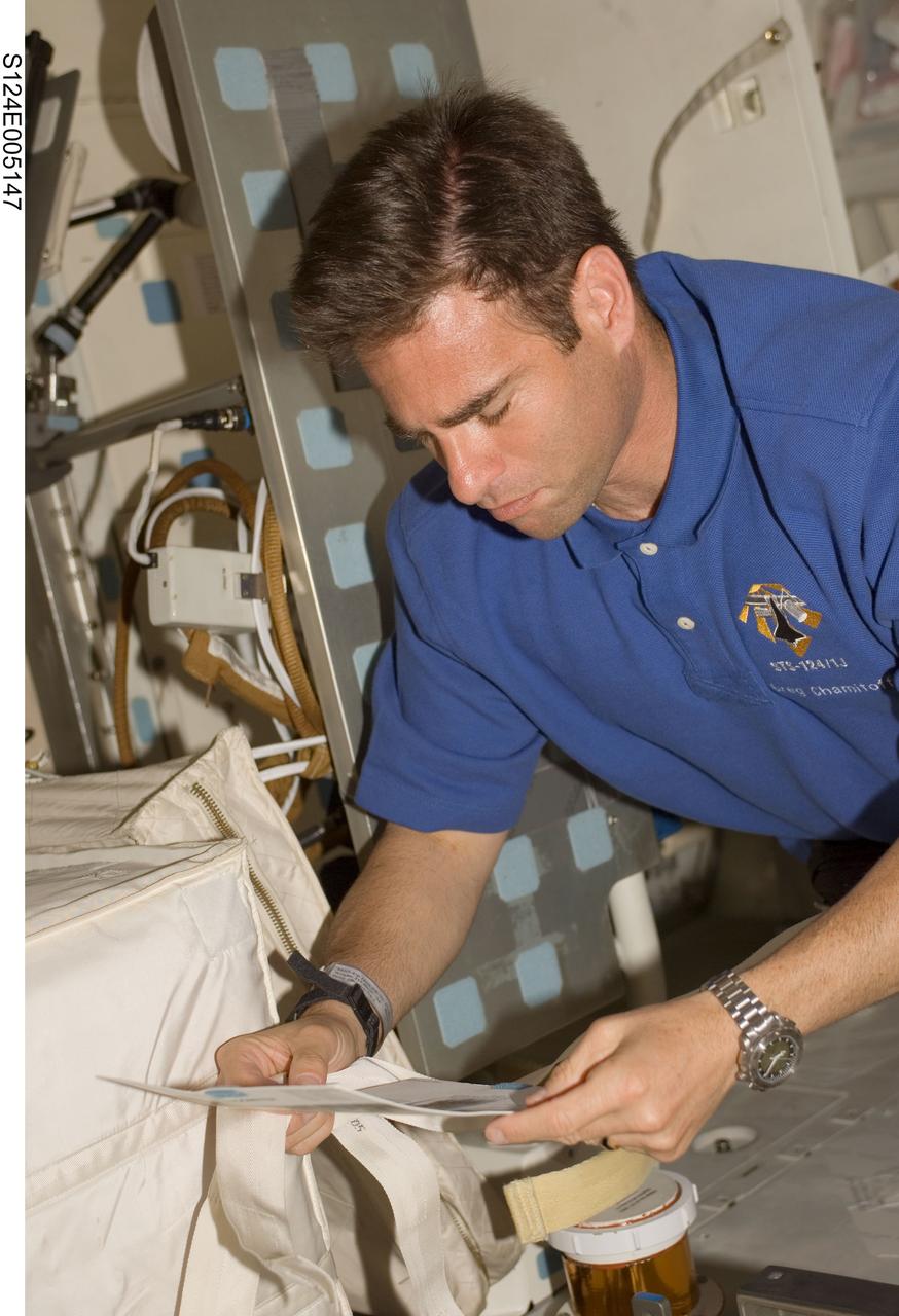 S124-E-005147 (1 June 2008) --- Astronaut Greg Chamitoff, STS-124 mission specialist, looks over a checklist on the middeck of Space Shuttle Discovery during flight day two activities.
