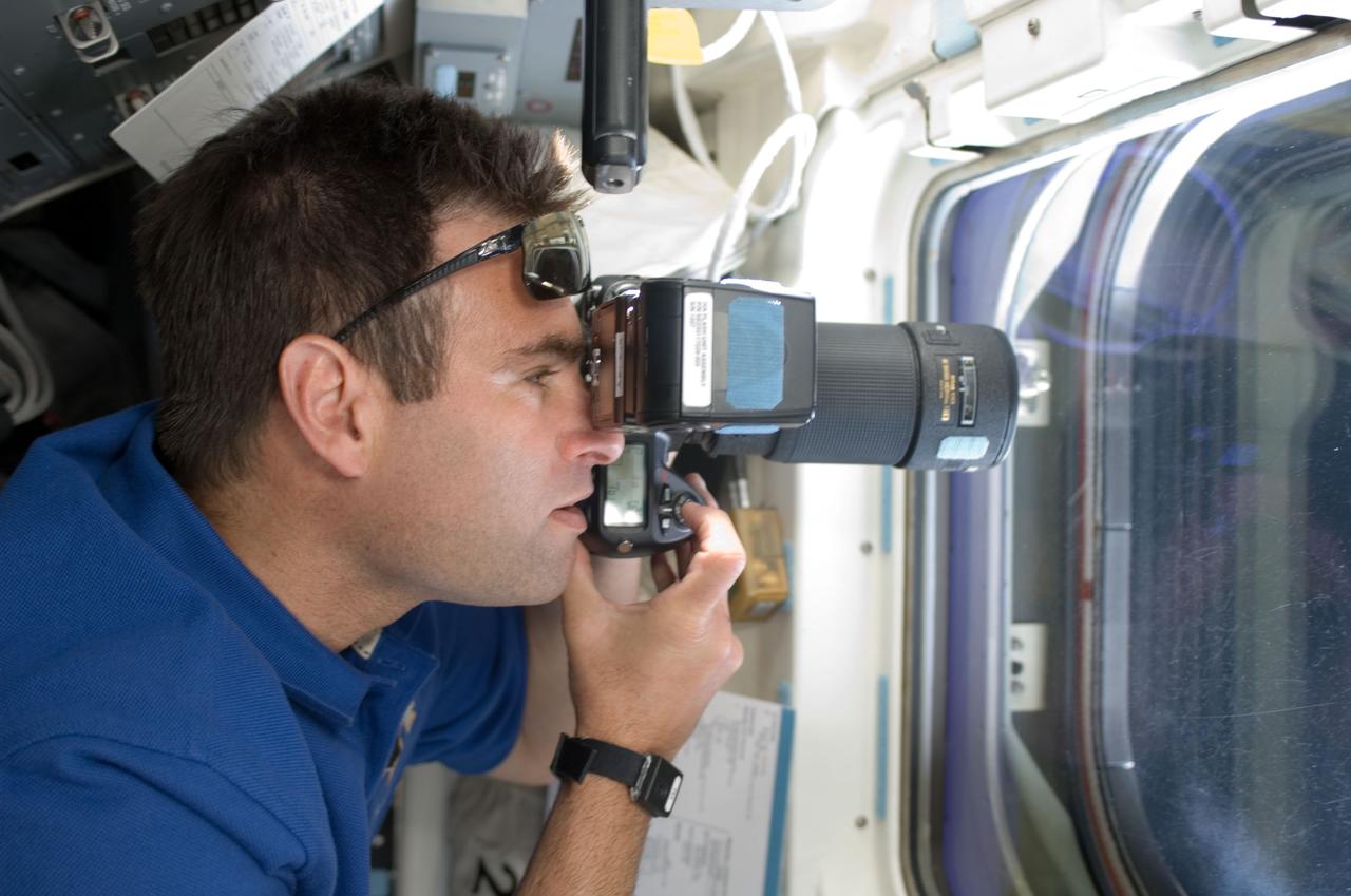 S124-E-005687 (2 June 2008) --- Astronaut Greg Chamitoff, STS-124 mission specialist, uses a still camera at a window on the aft flight deck of Space Shuttle Discovery during flight day three activities.