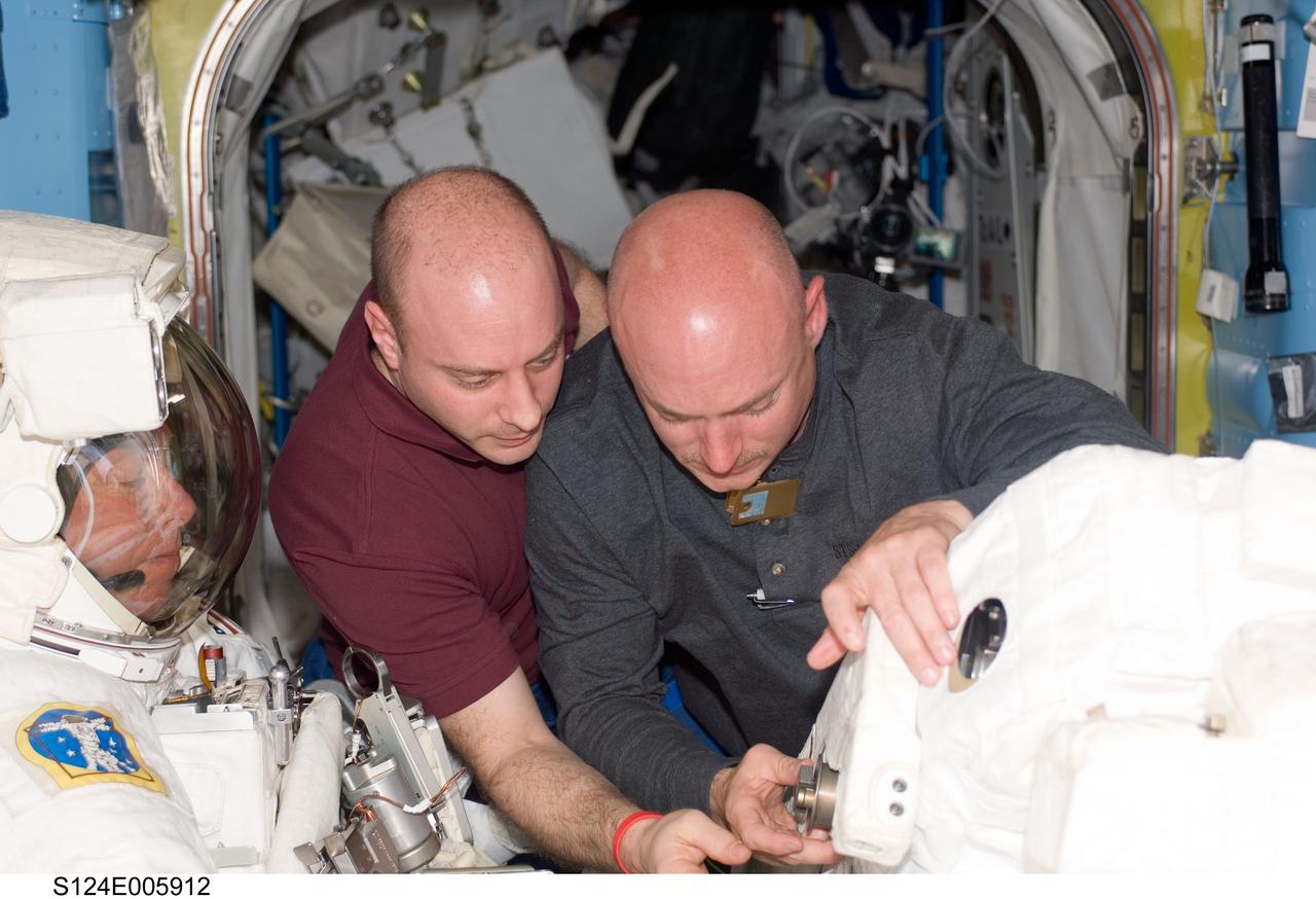 S124-E-005912 (3 June 2008) --- Astronauts Mark Kelly (right), STS-124 commander, and Garrett Reisman, mission specialist, assist astronauts Mike Fossum (left) and Ron Garan (out of frame), mission specialists, in the Quest Airlock of the International Space Station prior to the start of the mission's first scheduled session of extravehicular activity (EVA) while Space Shuttle Discovery is docked with the station.