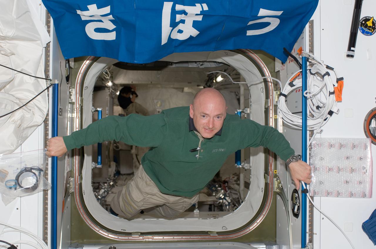 S124-E-006287 (4 June 2008) --- Astronaut Mark Kelly, STS-124 commander, floats in the hatch between the Harmony node and the newly installed Kibo Japanese Pressurized Module (JPM) of the International Space Station while Space Shuttle Discovery is docked with the station.