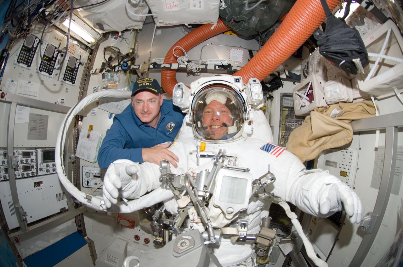 S124-E-007218 (8 June 2008) --- A "fish-eye" lens on a digital still camera was used to record this image of astronauts Mark Kelly (left) and Mike Fossum, STS-124 commander and mission specialist, respectively, in the Quest Airlock of the International Space Station while Space Shuttle Discovery is docked with the station. Fossum and astronaut Ron Garan (out of frame) were about to begin the mission's third scheduled spacewalk.