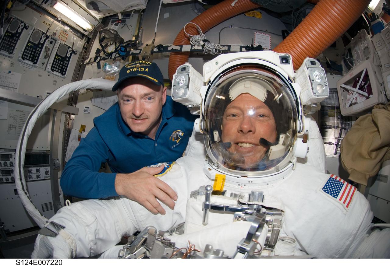 S124-E-007220 (8 June 2008) --- A "fish-eye" lens on a digital still camera was used to record this image of astronauts Mark Kelly (left) and Mike Fossum, STS-124 commander and mission specialist, respectively, in the Quest Airlock of the International Space Station while Space Shuttle Discovery is docked with the station. Fossum and astronaut Ron Garan (out of frame) were about to begin the mission's third scheduled spacewalk.