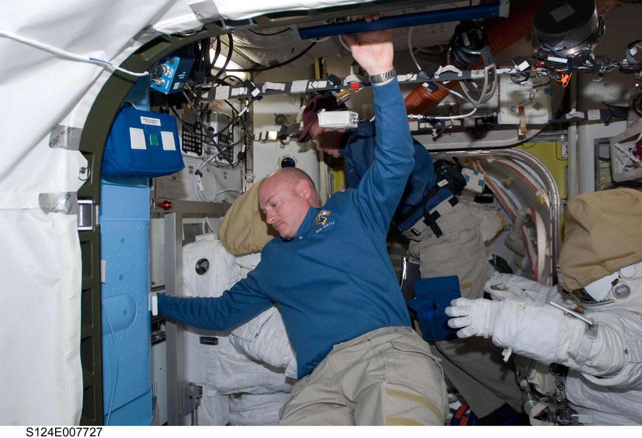 S124-E-007727 (7 June 2008) --- Astronauts Mark Kelly (foreground), STS-124 commander, and Mike Fossum, mission specialist, check on a couple of details related to the following day's scheduled spacewalk. The two extravehicular mobility unit (EMU) space suits seen here will be worn by astronauts Fossum and Ron Garan (out of frame) for the third and final scheduled spacewalk for Discovery's mission at the International Space Station.