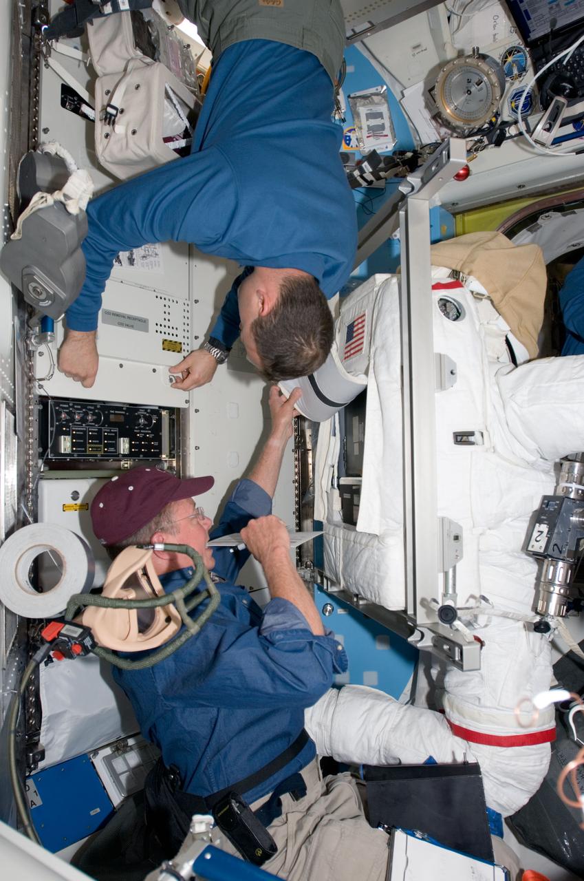 S124-E-007740 (7 June 2008) --- Astronauts Ron Garan (left) and Mike Fossum, both STS-124 mission specialists, work with Extravehicular Mobility Unit (EMU) spacesuits in the Quest Airlock of the International Space Station while Space Shuttle Discovery is docked with the station.