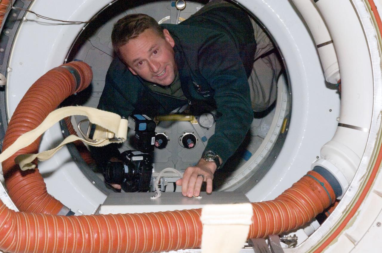 S124-E-007747 (9 June 2008) --- Astronaut Ken Ham, STS-124 pilot, holds a still camera as he moves through Space Shuttle Discovery's orbiter docking system while docked with the International Space Station.