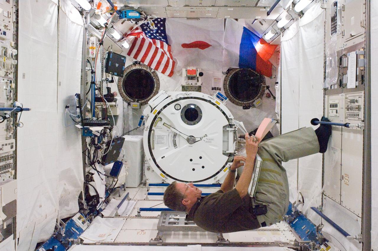 S124-E-007863 (9 June 2008) --- Astronaut Mike Fossum, STS-124 mission specialist, looks over checklists in the Kibo Japanese Pressurized Module of the International Space Station while Space Shuttle Discovery is docked with the station.