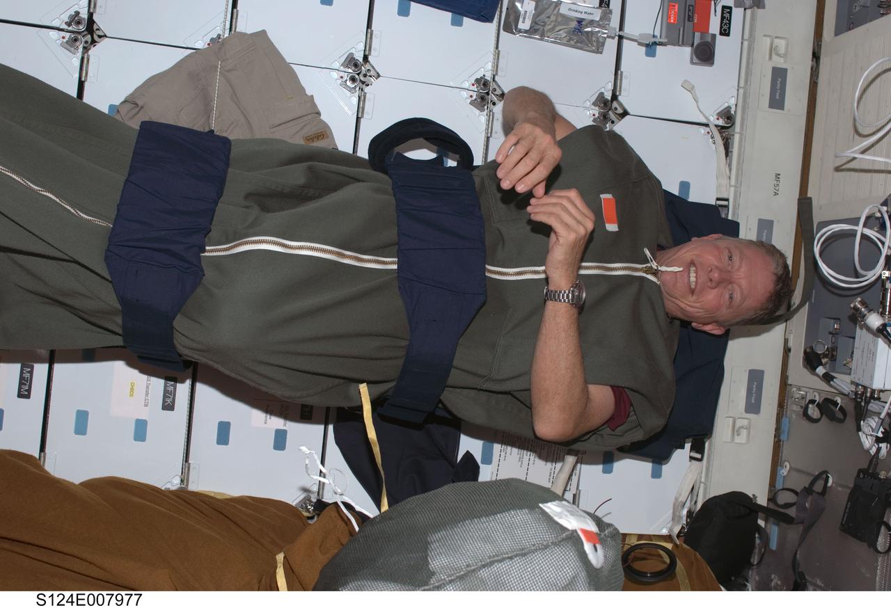 S124-E-007977 (9 June 2008) --- Astronaut Mike Fossum, STS-124 mission specialist, is pictured in his sleeping bag, which is attached to the lockers on the middeck of the Space Shuttle Discovery, while docked with the International Space Station.