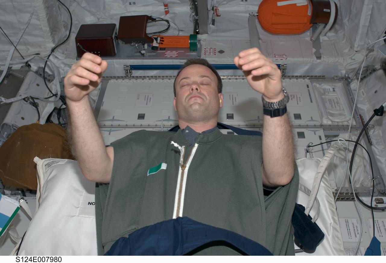 S124-E-007980 (9 June 2008) --- Astronaut Ron Garan, STS-124 mission specialist, sleeps in his sleeping bag in the Columbus laboratory of the International Space Station while Space Shuttle Discovery is docked with the station.