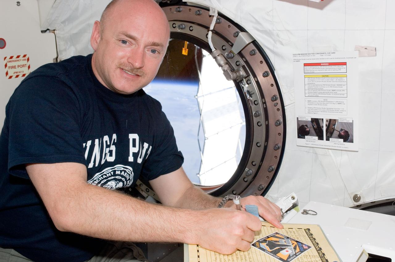 S124-E-008449 (10 June 2008) --- Astronaut Mark Kelly, STS-124 commander, makes an entry in the International Space Station ship's log in the Kibo laboratory while Space Shuttle Discovery is docked with the station. Also visible in the log is the STS-124 mission logo.