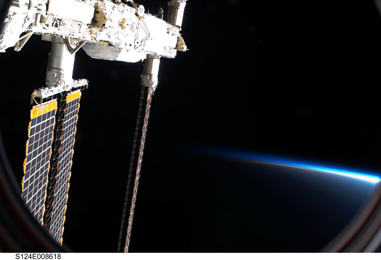 S124-E-008618 (10 June 2008) --- A partial view of International Space Station solar panels and Earth's atmosphere are photographed by a STS-124 crewmember on the International Space Station while Space Shuttle Discovery is docked with the station.