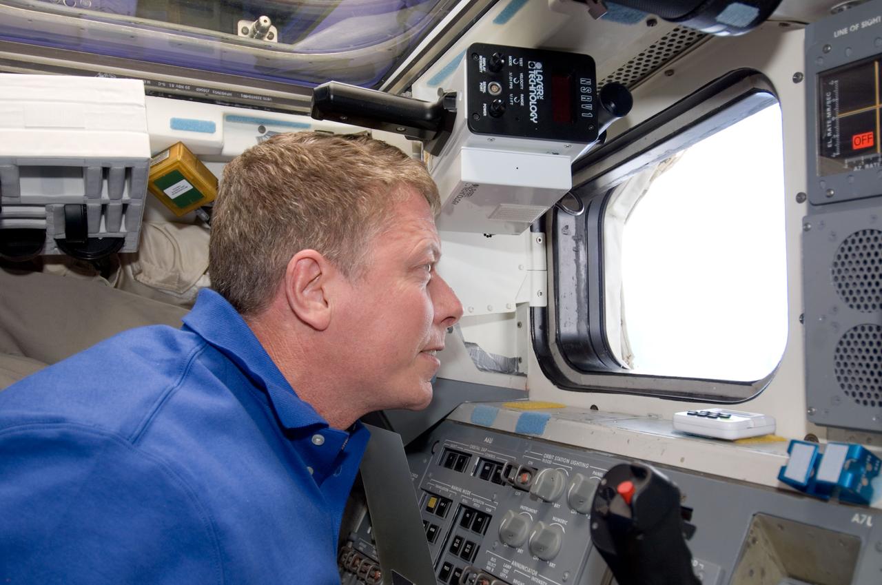 S124-E-009888 (10 June 2008) --- Astronaut Mike Fossum, STS-124 mission specialist, looks through a window on the aft flight deck of Space Shuttle Discovery while docked with the International Space Station.