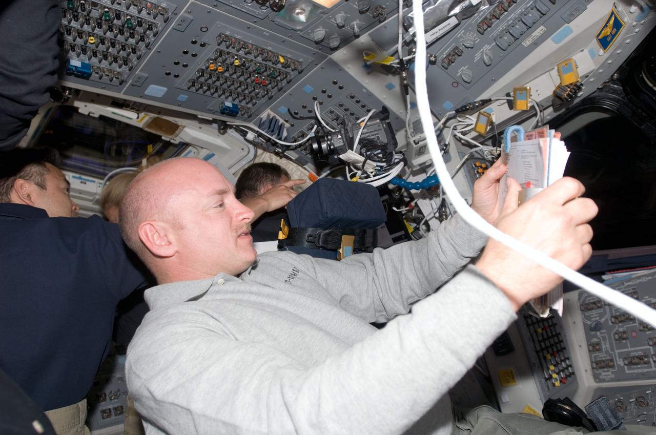 S124-E-009906 (11 June 2008) --- Astronaut Mark Kelly, STS-124 commander, looks over a checklist on the flight deck of Space Shuttle Discovery during flight day 12 activities.
