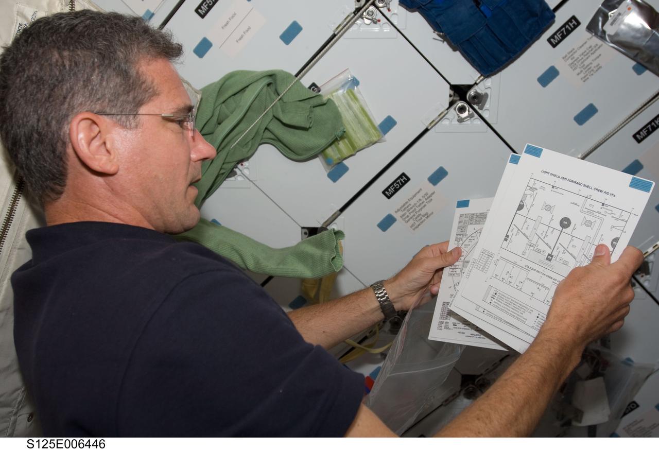 S125-E-006446 (12 May 2009) --- Astronaut Michael Good, STS-125 mission specialist, looks over charts on Atlantis? mid deck during his second day in space. The next several days prove to be very busy for the entire crew, as five spacewalks, two of which will have Good leaving the shirt sleeved environment of the shuttle to perform work on the Hubble Space Telescope, are in the offing.