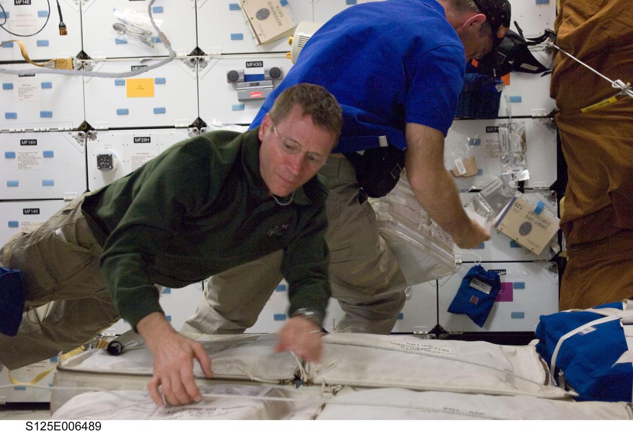 S125-E-006489 (12 May 2009) --- Astronaut Gregory C. Johnson, pilot, helps with unpacking chores on Atlantis? mid deck during the STS-125 flight?s second day in space.