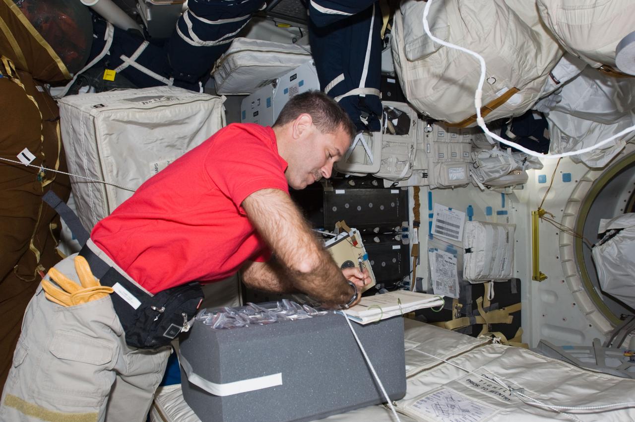 S125-E-006501 (12 May 2009) --- Astronaut John Grunsfeld, mission specialist, helps with unpacking chores on Atlantis? mid deck during the STS-125 flight?s second day in space.  The next several days prove to be very busy for the entire crew, as five spacewalks, three of which will have the veteran Grunsfeld leaving the shirt sleeved environment of the shuttle, are in the offing.