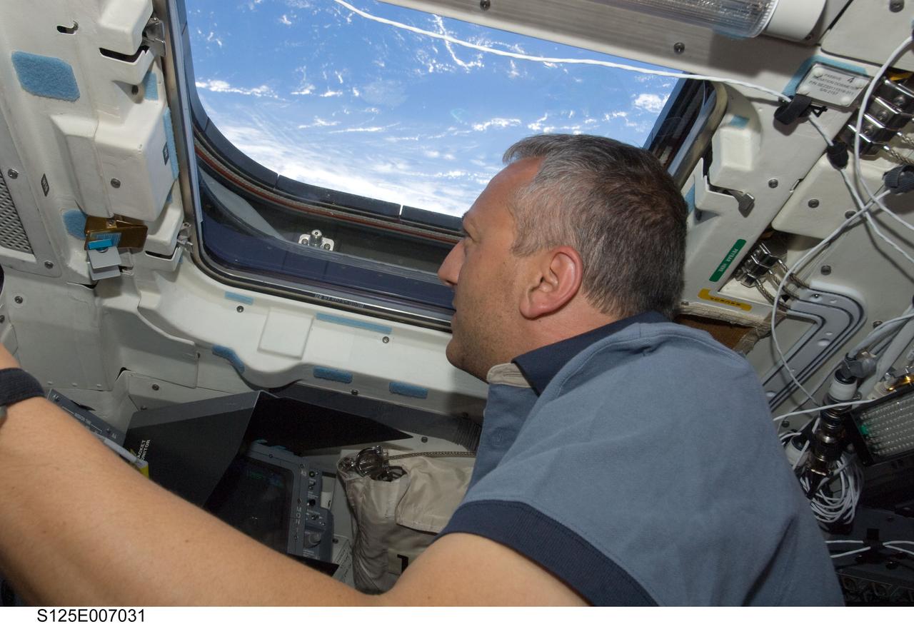 S125-E-007031 (13 May 2009) --- Astronaut Mike Massimino, STS-125 mission specialist, looks through an overhead window on the aft flight deck of Space Shuttle Atlantis during flight day three activities.