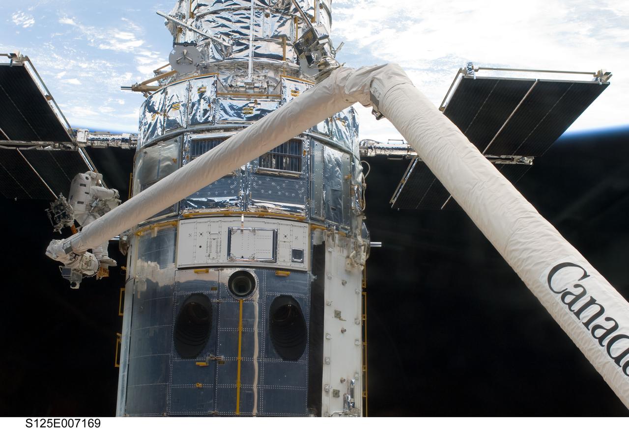 S125-E-007169  (14 May 2009) --- Astronaut  Andrew Feustel, perched alone on the end of the Space Shuttle Atlantis? remote manipulator system arm, participates in the first of five STS-125 spacewalks to perform work on the Hubble Space Telescope, temporarily locked down in the cargo bay of the Earth-orbiting shuttle.  Out of frame is his space-walking colleague, veteran astronaut John Grunsfeld.  The two mission specialists are also assigned to two of the remaining four sessions of extravehicular activity for the Atlantis crew.
