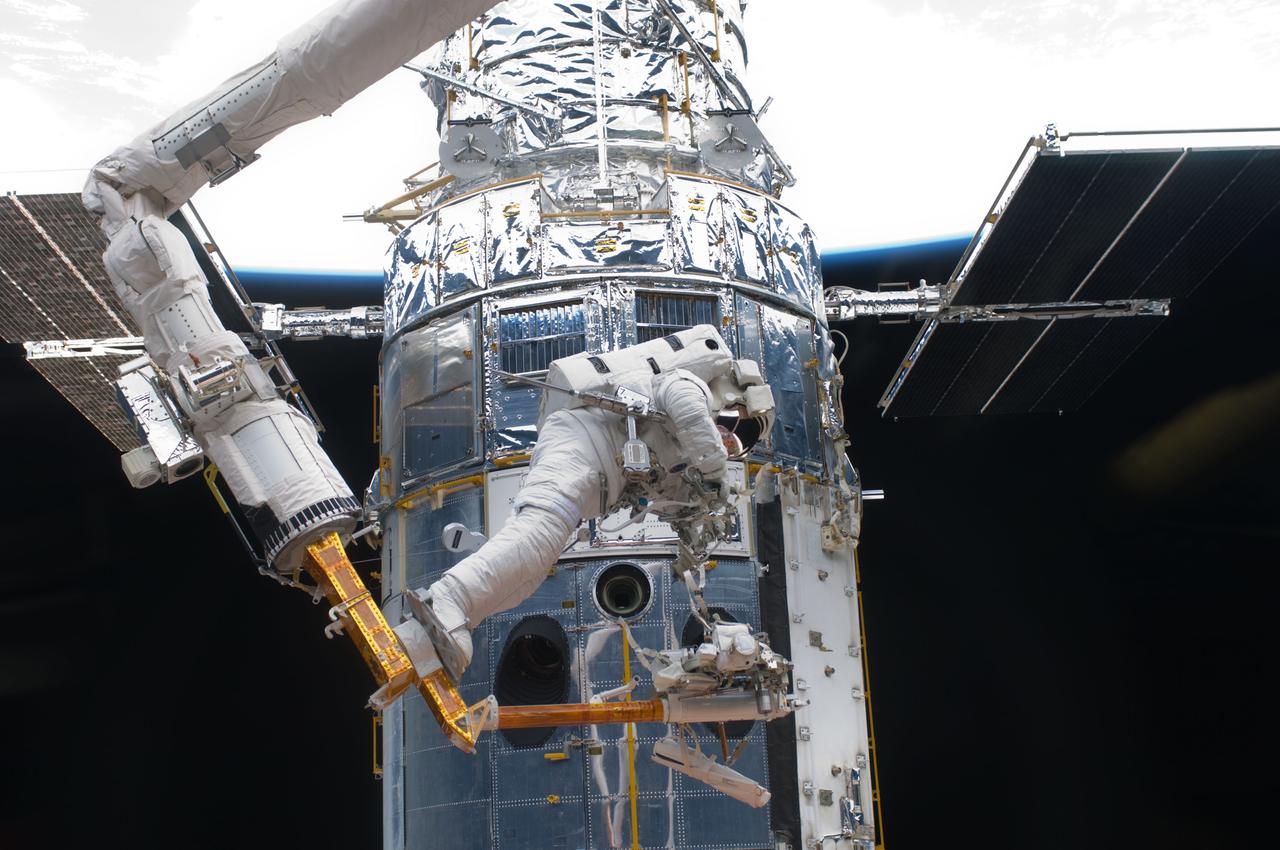 S125-E-007174 (14 May 2009) --- Perched on the end of the Canadian-built remote manipulator system, astronaut Andrew Feustel, mission specialist,  performs work on the Hubble Space Telescope as the first of five STS-125 spacewalks kicks off a week?s work on the orbiting observatory. Feustel, teamed with  astronaut John Grunsfeld (out of frame),  will join the veteran spacewalker on two of the remaining four sessions of extravehicular activity later in the mission.