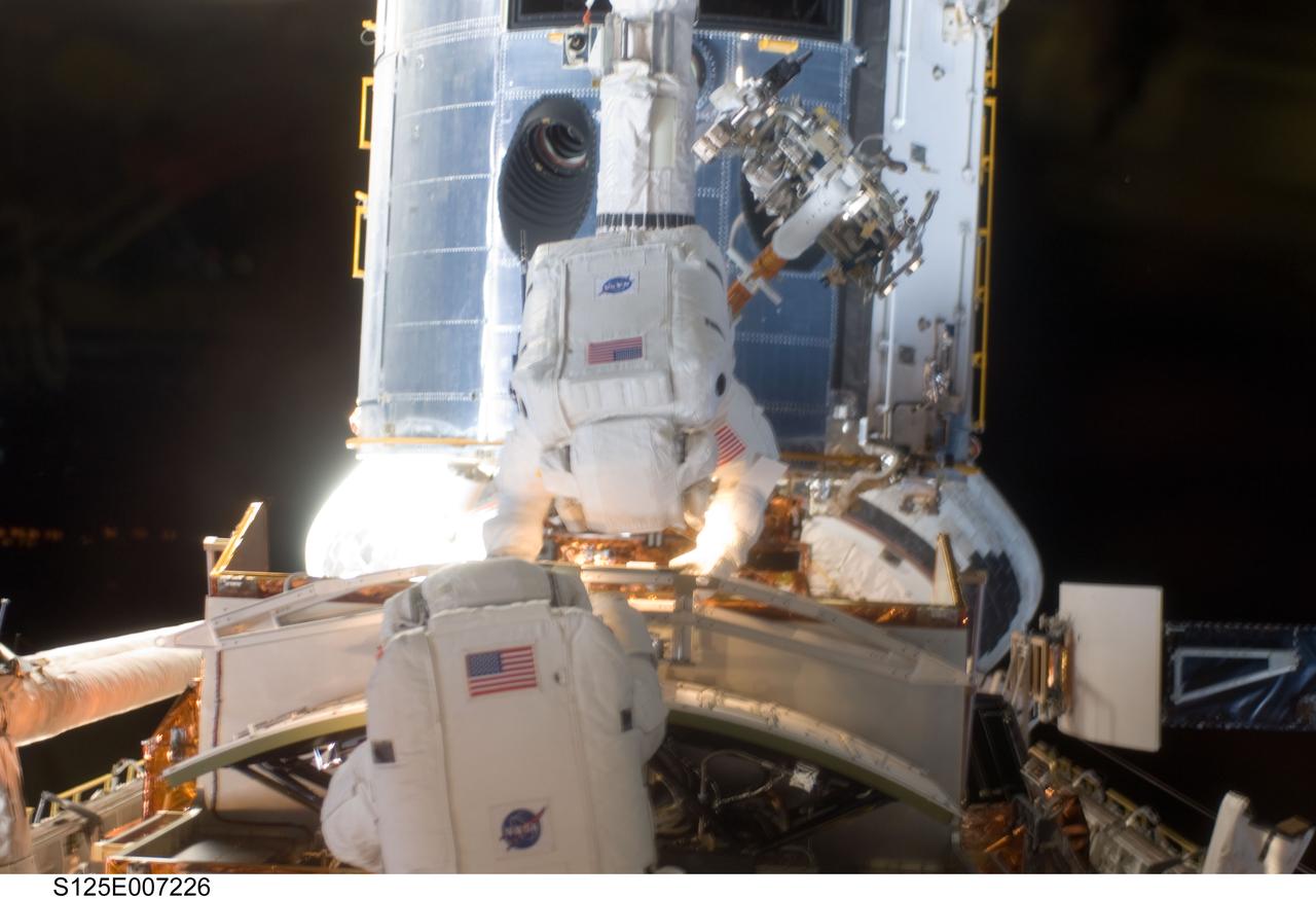 S125-E-007226 (14 May 2009) --- Astronauts John Grunsfeld (bottom) and Andrew Feustel share work on the temporarily-captured Hubble Space Telescope, in the cargo bay of the Earth-orbiting Space Shuttle Atlantis. The mission specialists are performing the first of five STS-125 spacewalks and the first of three for this duo.
