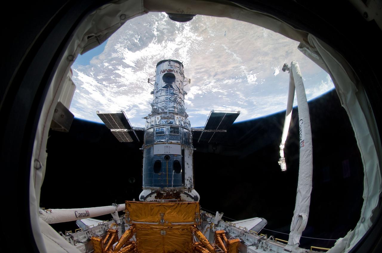 S125-E-007257 (14 May 2009) --- A wide view of the Hubble Space Telescope, locked down in the cargo bay of the Earth-orbiting Space Shuttle Atlantis, which will be site of a great deal of hands-on servicing over the next five days. The Canadian-built remote manipulator system arm (right), with its video cameras documenting activity in the shuttle's cargo bay all week, was instrumental in grappling and subsequently capturing the giant orbital observatory for the final servicing mission.