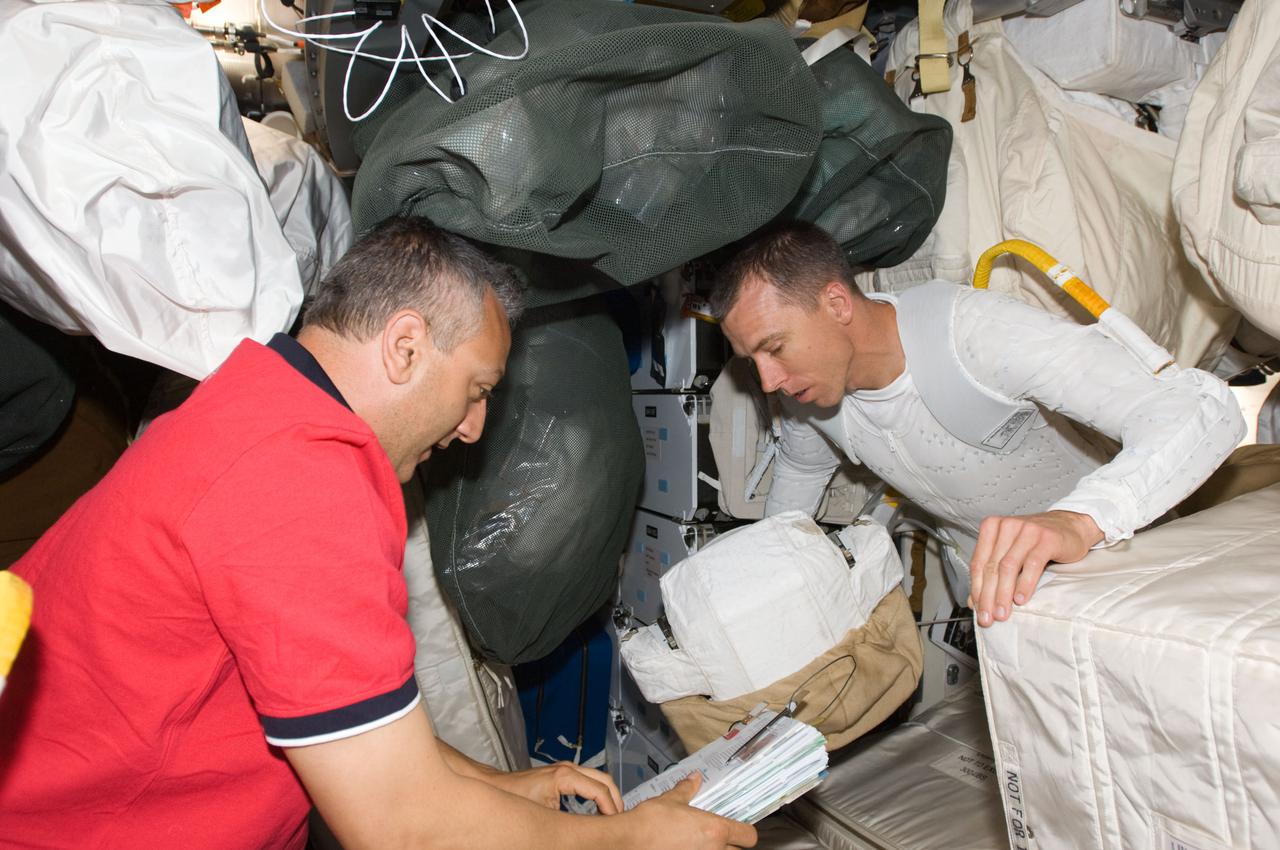 S125-E-007291 (14 May 2009) --- Astronauts Mike Massimino (left) and Andrew Feustel, both STS-125 mission specialists, look over a procedures checklist on the middeck of Space Shuttle Atlantis prior to the mission?s first session of extravehicular activity (EVA). Feustel is wearing the liquid cooling and ventilation garment that complements the Extravehicular Mobility Unit (EMU) spacesuit.