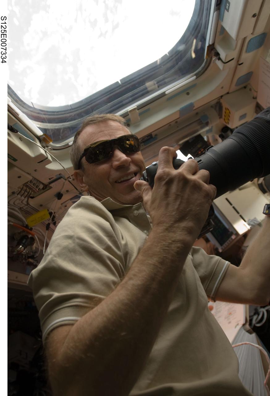 S125-E-007334 (14 May 2009) --- Astronaut Gregory C. Johnson, STS-125 pilot, uses a still camera at an overhead window on the aft flight deck of Space Shuttle Atlantis during flight day four activities.
