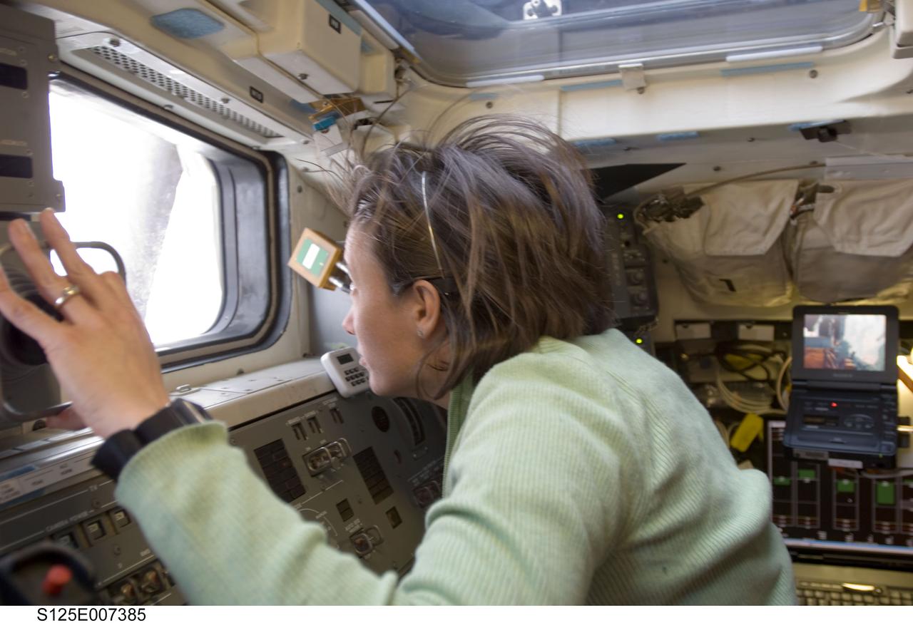 S125-E-007385 (14 May 2009) --- Astronaut Megan McArthur, STS-125 mission specialist, looks through a window while working controls on the aft flight deck of Space Shuttle Atlantis.