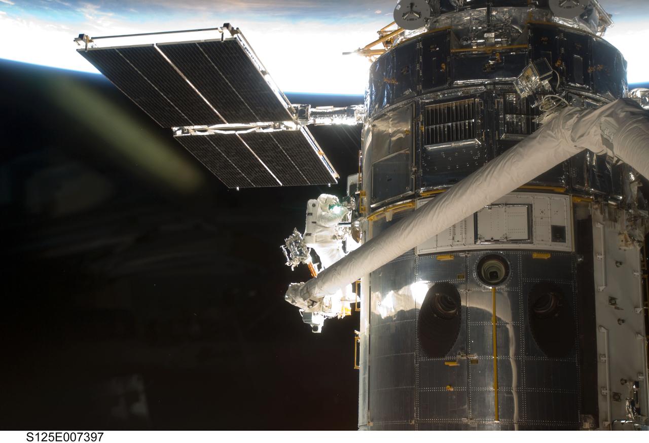 S125-E-007397  (14 May 2009) --- Astronaut  Andrew Feustel, perched alone on the end of the Space Shuttle Atlantis? remote manipulator system arm, participates in the first of five STS-125 spacewalks to perform work on the Hubble Space Telescope, temporarily locked down in the cargo bay of the Earth-orbiting shuttle.  Out of frame is his space-walking colleague, veteran astronaut John Grunsfeld.  The two mission specialists are also assigned to two of the remaining four sessions of extravehicular activity for the Atlantis crew.