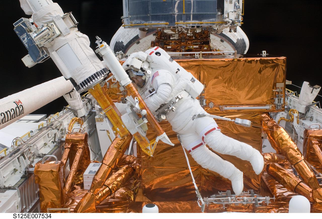 S125-E-007534 (15 May 2009) --- Astronaut Mike Massimino works with the Hubble Space Telescope in the cargo bay of the Earth-orbiting Space Shuttle Atlantis. Astronauts Massimino and Michael Good (out of frame) participated in the second session of STS-125 extravehicular activity -- as part of a five-day beehive-like agenda of spacewalking and work on the giant orbital observatory.