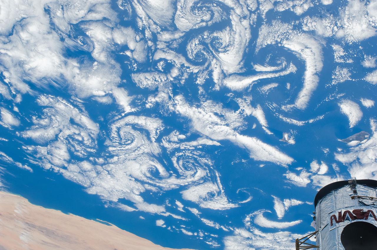 S125-E-007547 (15 May 2009) --- Low-level winds rushing over the Cape Verde Islands off the coast of northwestern Africa created cloud vortex streets which share this scene with the top of the Hubble Space Telescope locked down in the cargo bay of the Earth-orbiting Space Shuttle Atlantis.
