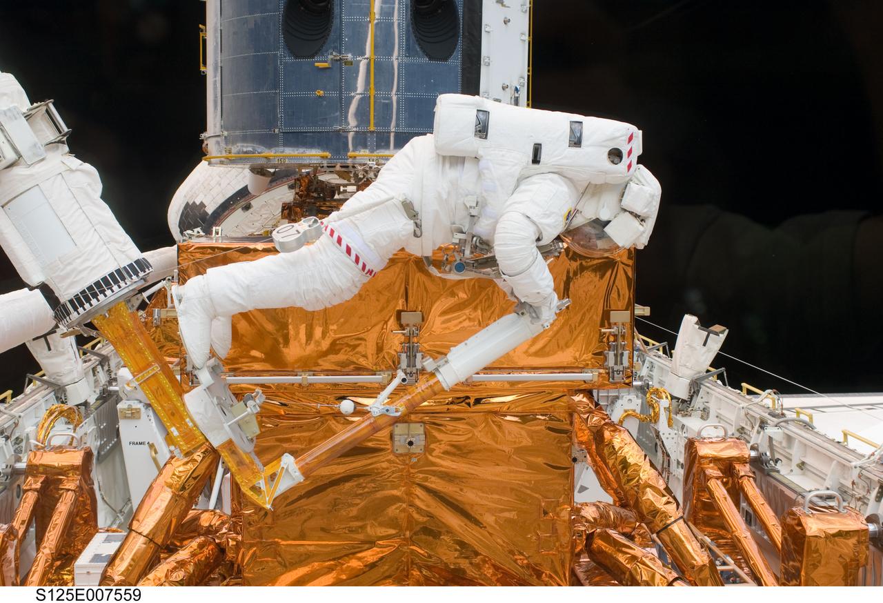 S125-E-007559 (15 May 2009) --- Astronaut Michael Good works with the Hubble Space Telescope in the cargo bay of the Earth-orbiting Space Shuttle Atlantis. Astronauts Good and Mike Massimino (out of frame) participated in the second session of STS-125 extravehicular activity -- as part of a five-day beehive-like agenda of spacewalking and work on the giant orbital observatory.